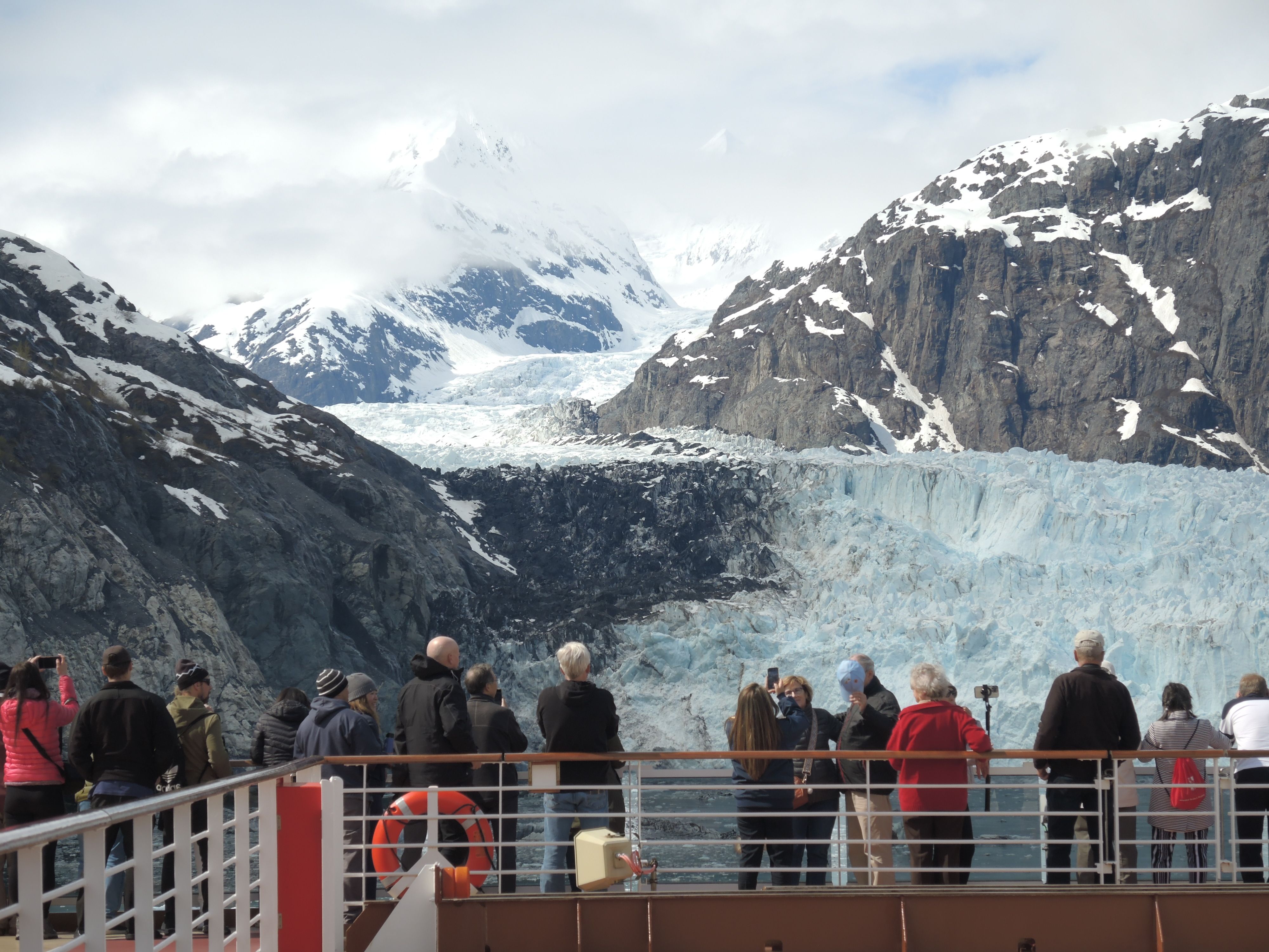Tourists admiring a glacier from a cruise ship deck in Alaska